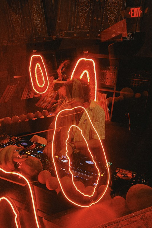 DJ set with neon papaya lights at night